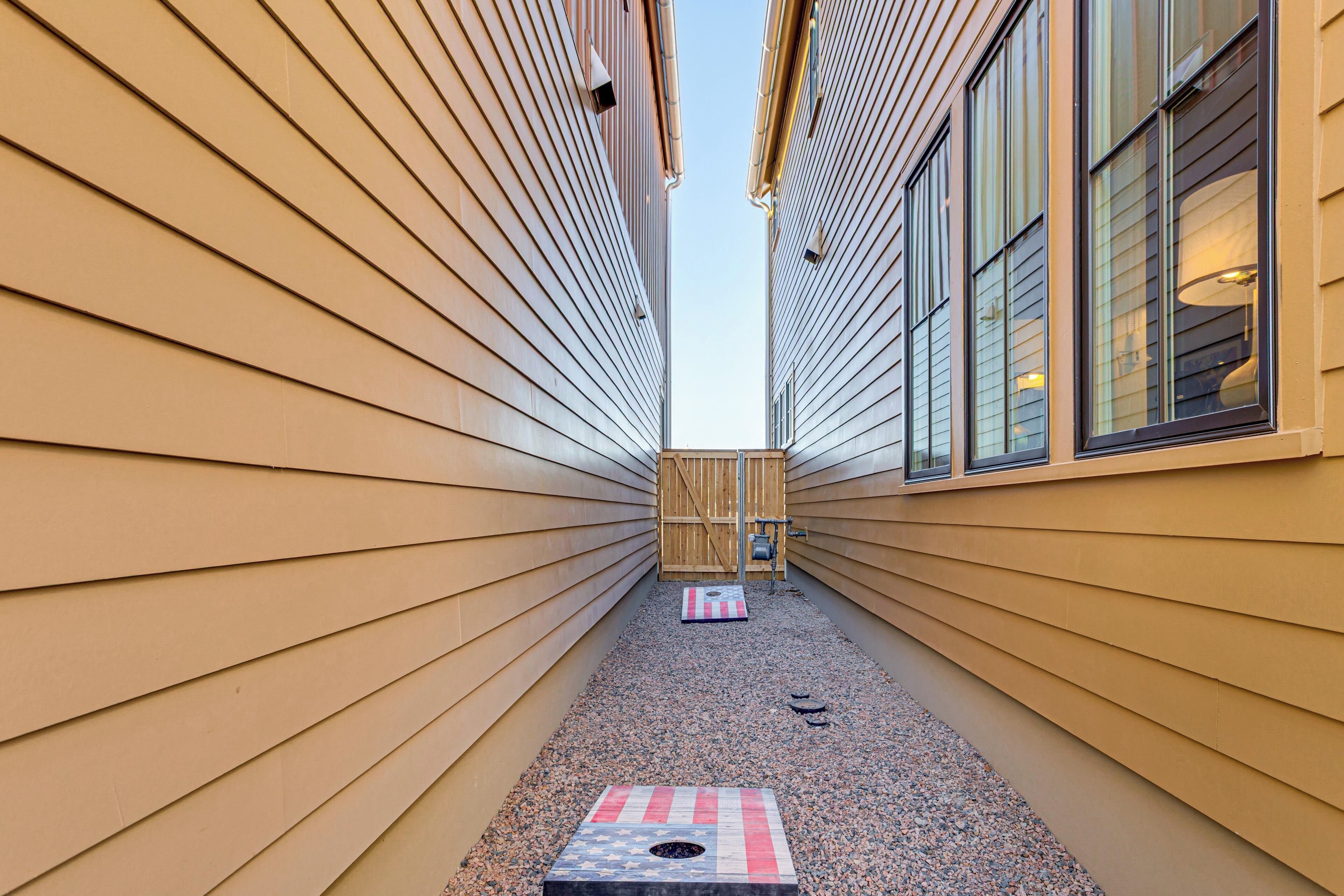 A narrow pathway with wooden siding walls and a gravel path leading to a wooden gate.
