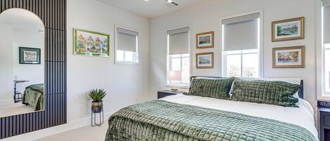 Un dormitorio con una cama grande, un espejo y varias ventanas.