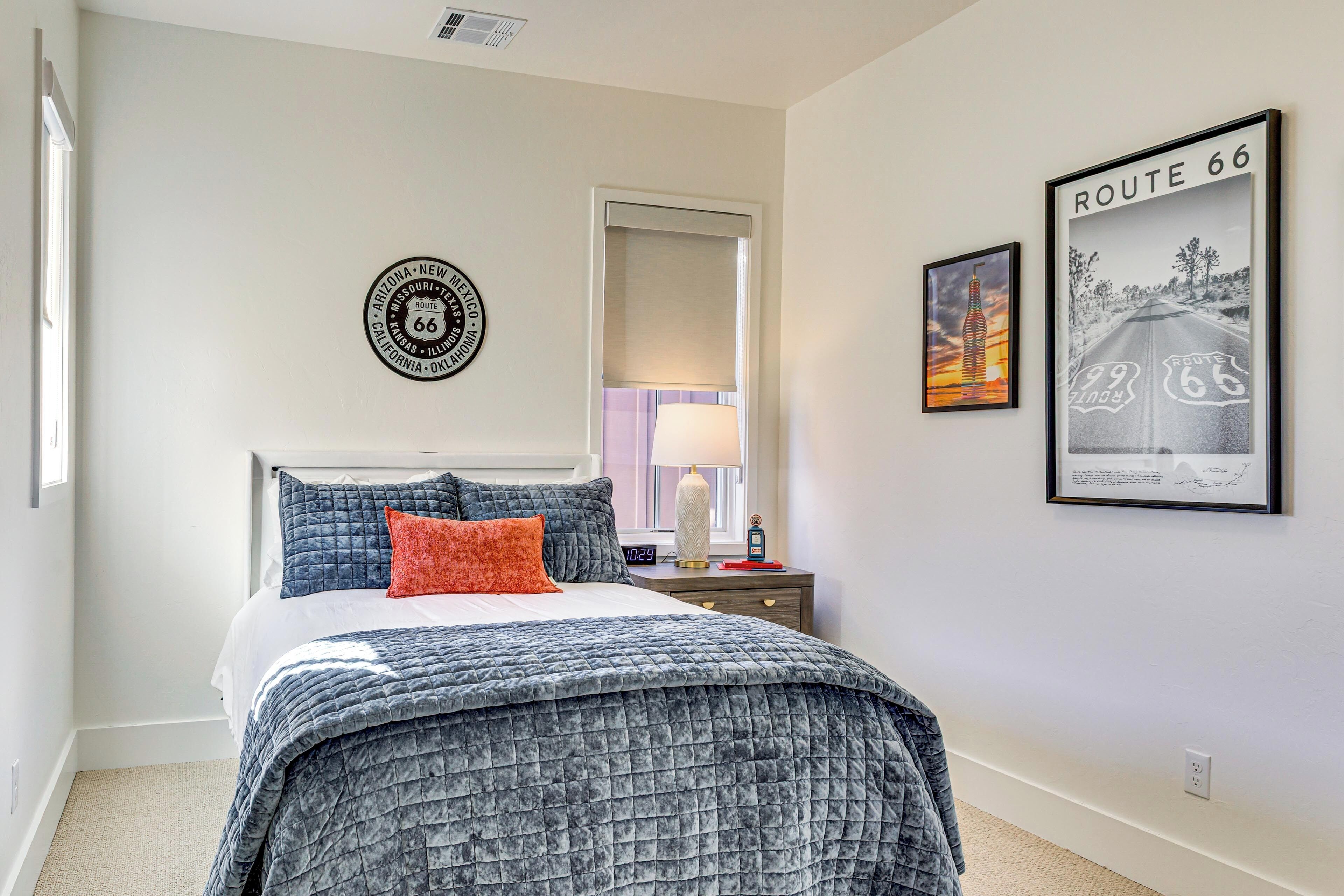 A bedroom with a bed, a nightstand, a lamp, and Route 66 themed wall art.