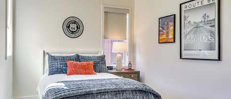 A bedroom with a bed, a nightstand, a lamp, and Route 66 themed wall art.