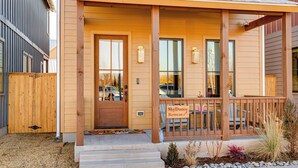 A wooden house with a porch, a sign reading "SkyDance Retreat," and a small garden area with rocks and plants. - Designer Wheeler Retreat: Walk to Dining! (Oklahoma City)