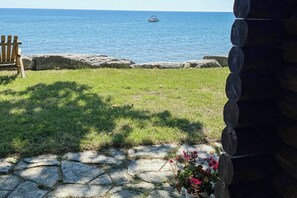 Un muro de piedra, una silla de madera, un sendero de piedra y vista al mar.