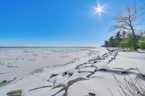 Una playa nevada bajo un cielo despejado y un sol radiante.