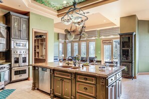 A spacious kitchen with a large island, built-in appliances, and a decorative ceiling fan.
