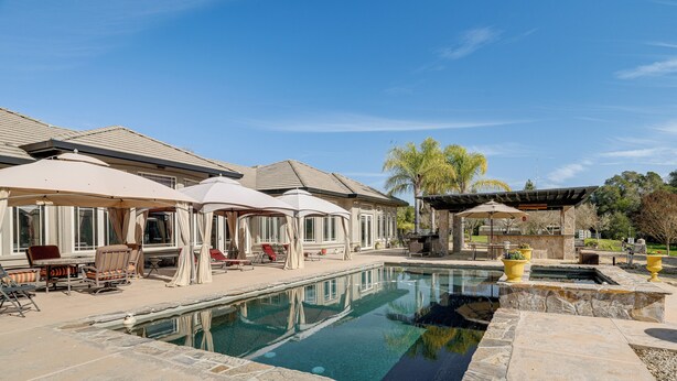 A swimming pool with lounge chairs and umbrellas, surrounded by stone tiles and a pergola. - Pool, Peacocks & Views! Lavish Retreat in Gilroy (Gilroy)