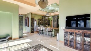 A spacious kitchen with a dining area, featuring a large island, dark wooden cabinets, and a modern chandelier. - Pool, Peacocks & Views! Lavish Retreat in Gilroy (Gilroy)