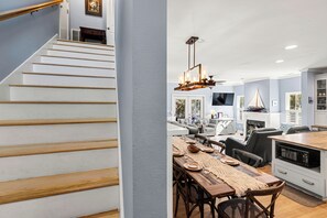 Una cocina moderna con una isla de madera, armarios blancos y un comedor con una mesa dispuesta para cuatro.