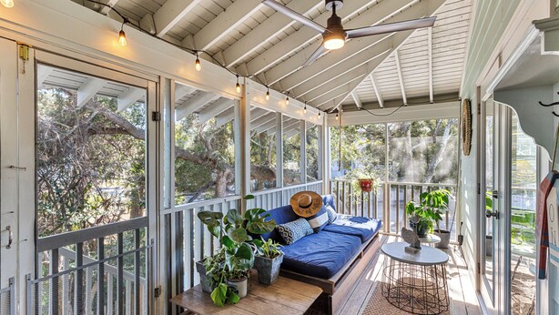 A covered porch with a wooden bench, a blue sofa, and potted plants. - Elevated Pet-Friendly Retreat Near the Beach (Tybee Island)