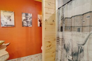 A bathroom with wooden walls, a shower curtain depicting a bull, and three framed pictures of bulls. - Family Escape Near Blue Ridge Ellijay (Ellijay)