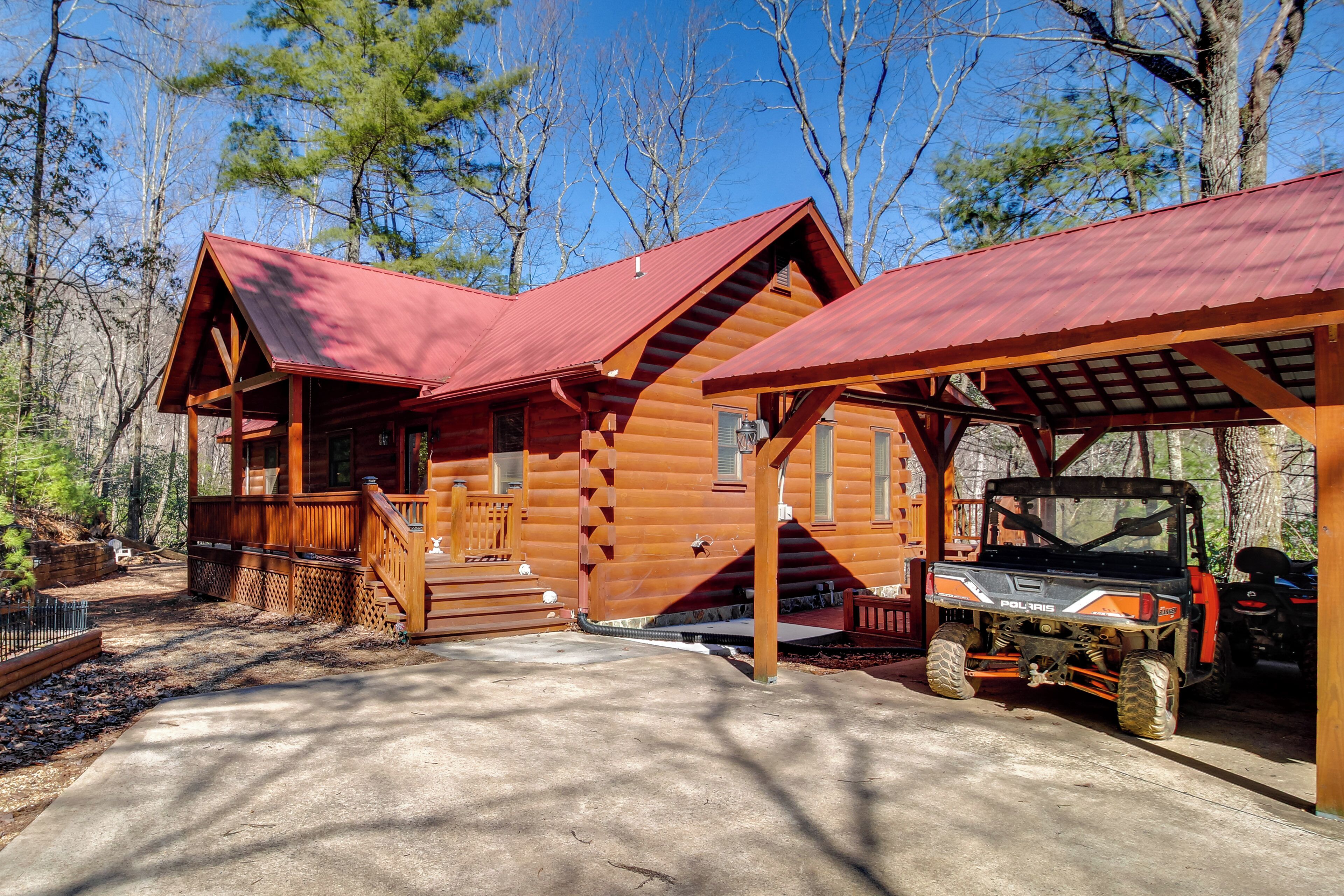 Eine Blockhütte mit überdachter Veranda und einem Polaris Quad vor der Tür.