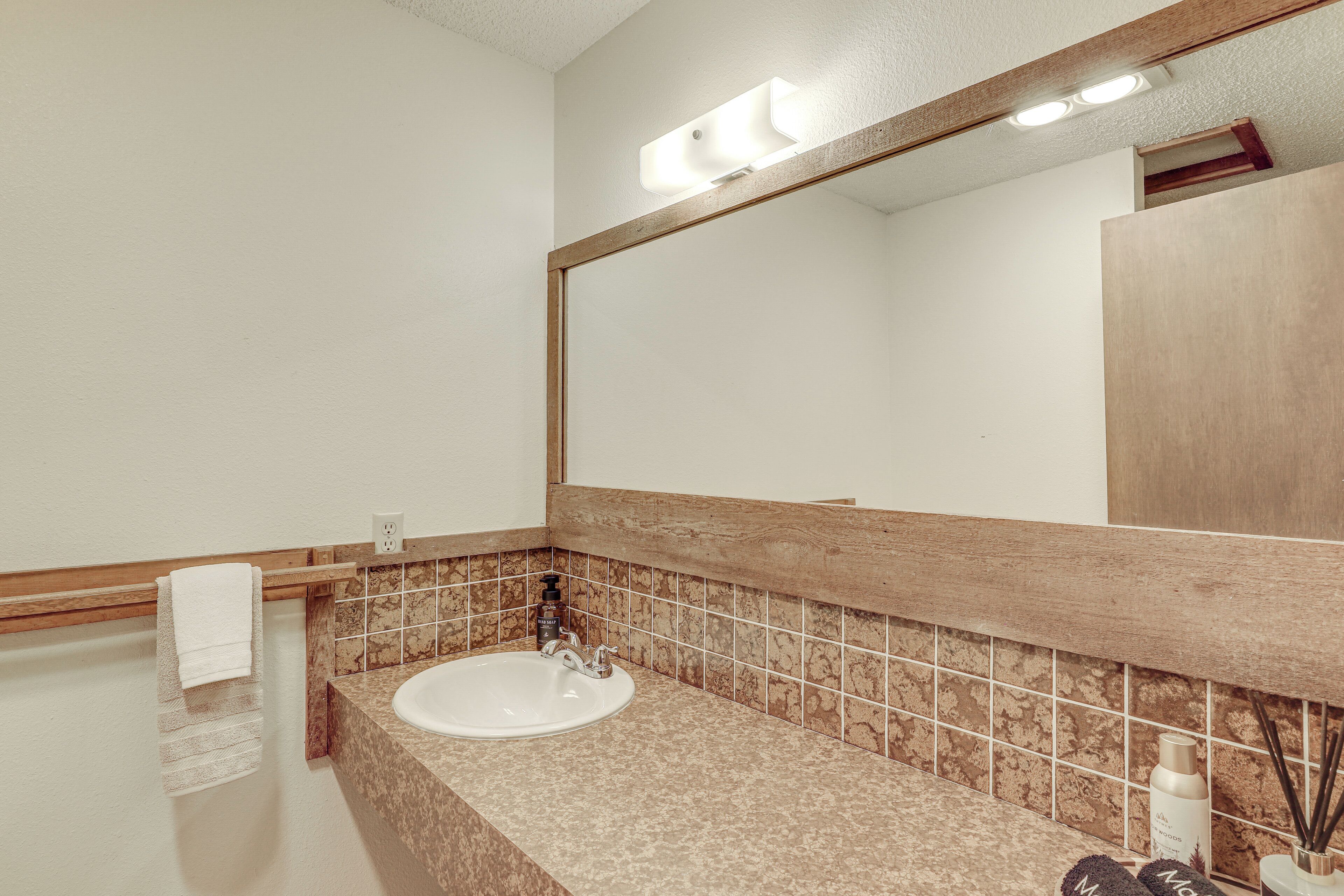 A bathroom with a sink, mirror, and towel rack.