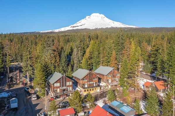 A lodge with multiple buildings, a road, and a forested area with a mountain in the background.