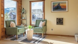 A cozy room with two green armchairs, a round coffee table, and a view of a mountain through large windows. - Après & Adventure: Mt Hood Retreat in Gov Camp! (Government Camp)