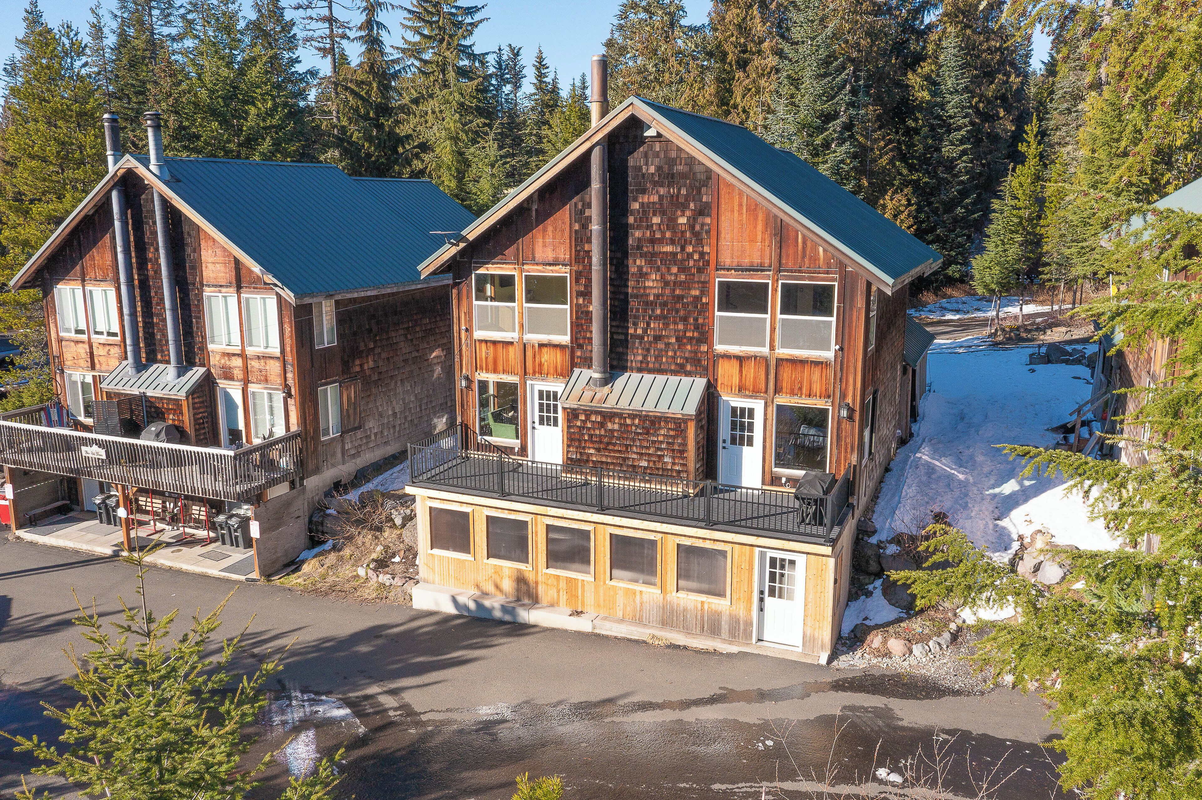 A wooden cabin with a balcony, large windows, and a chimney.