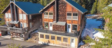 A wooden cabin with a balcony, large windows, and a chimney.