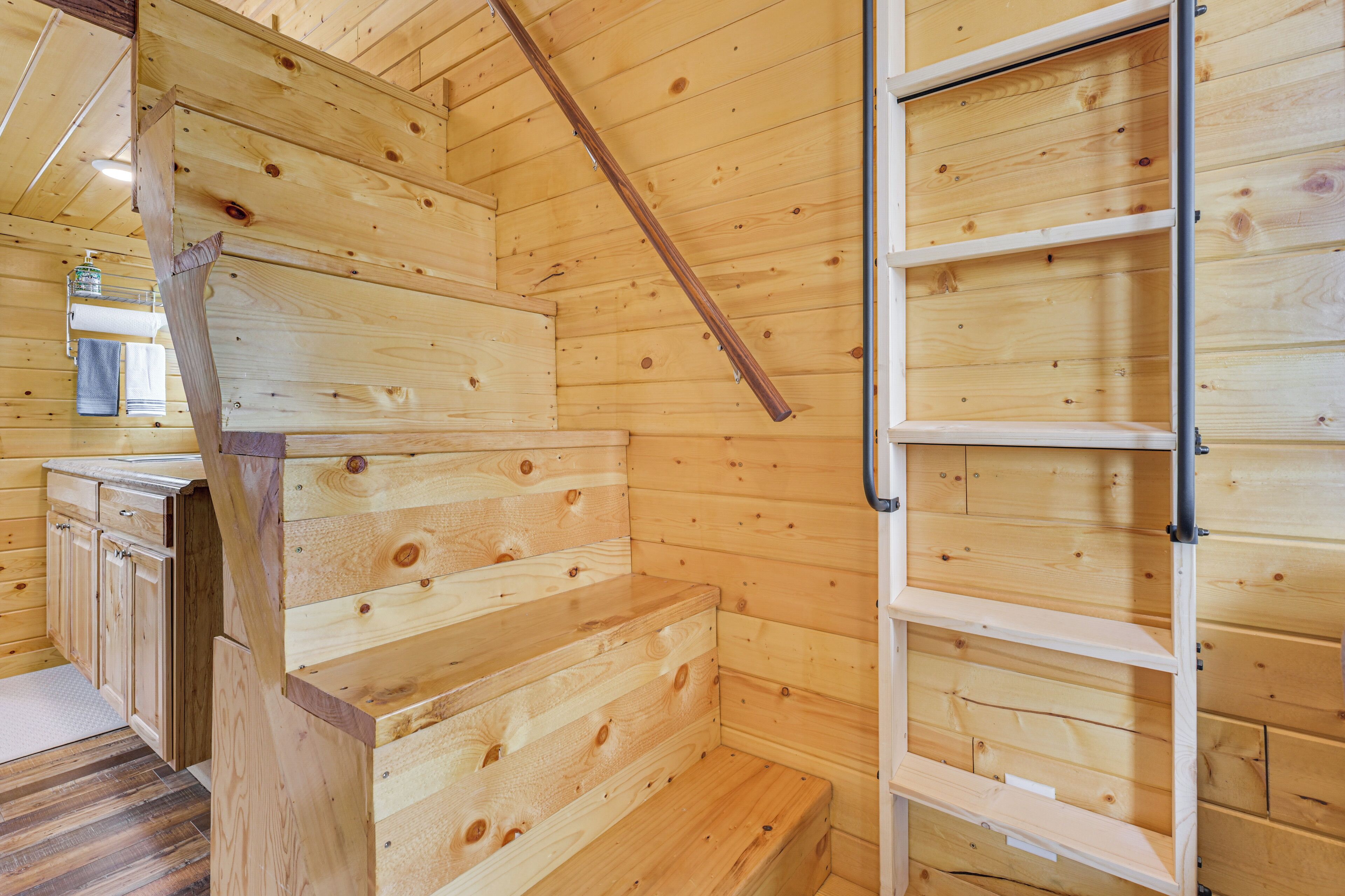 A wooden interior with a staircase, a built-in bench, and a metal ladder.