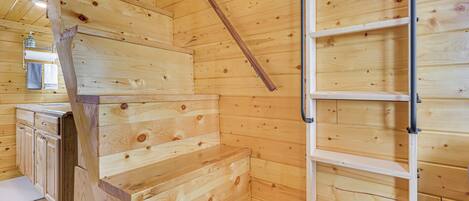 A wooden interior with a staircase, a built-in bench, and a metal ladder.