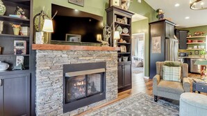 A living room with a stone fireplace, dark wooden cabinets, and a green accent wall. - Nature Meets Nashville! Mtn-view Home in Hickman (Hickman)