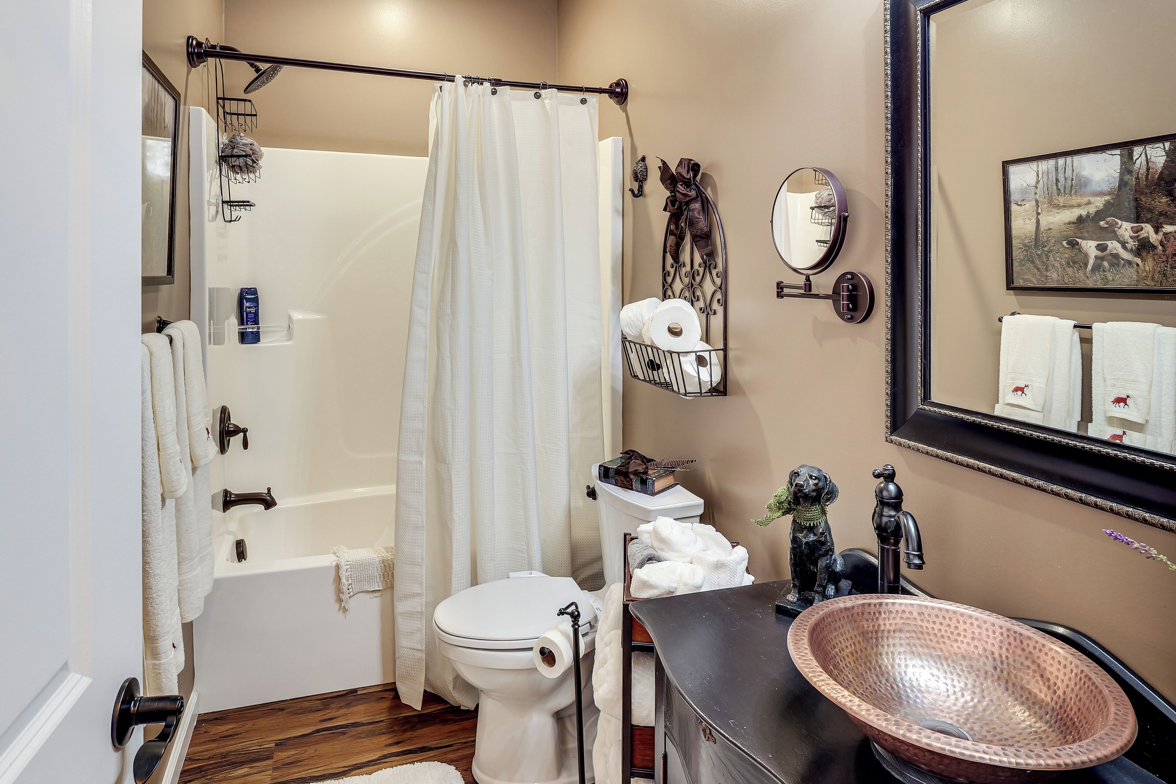 A bathroom with a bathtub, toilet, sink, and a large mirror.