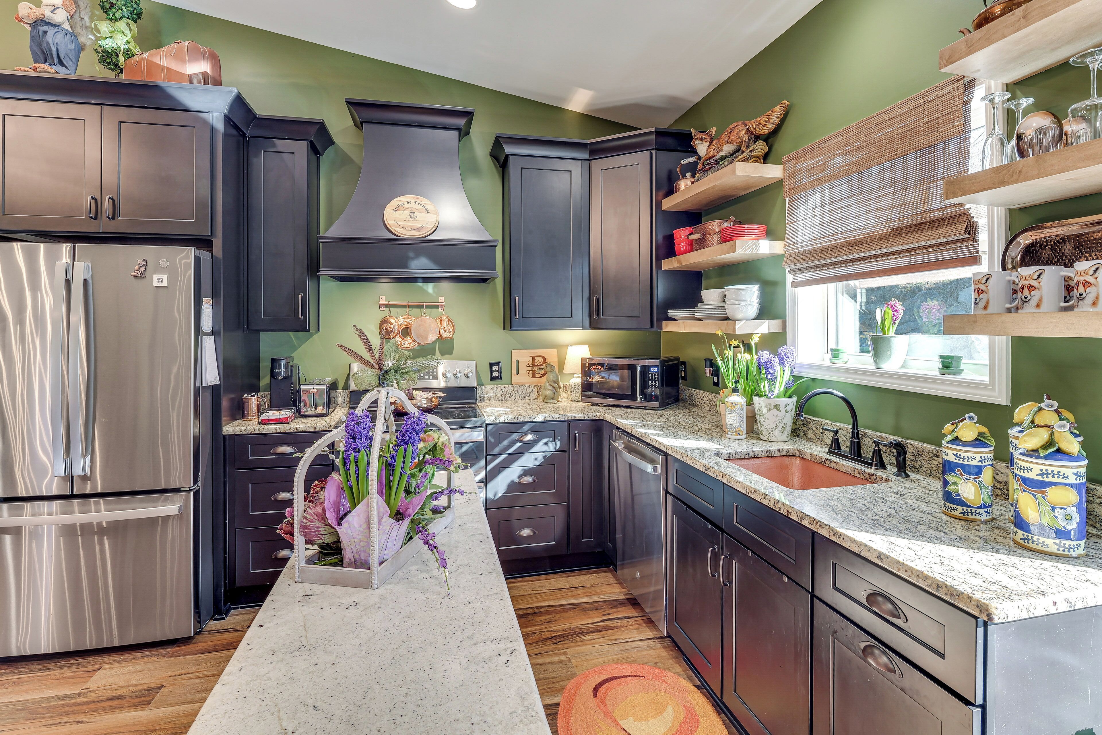 A modern kitchen with dark cabinetry, stainless steel appliances, and a granite countertop.