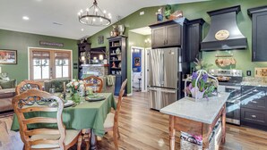 A modern kitchen with dark cabinetry, stainless steel appliances, and a green dining area. - Nature Meets Nashville! Mtn-view Home in Hickman (Hickman)