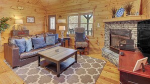 A cozy cabin interior with a stone fireplace, leather sofa, and a laptop on a wooden table. - Hot Tub + Mtn Views: Peaceful Blue Ridge Retreat! (Blue Ridge)