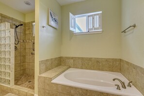 Un baño con ducha a nivel, bañera y ventana con contraventanas.