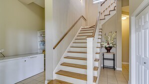 A staircase with wooden steps and white railings, leading to a landing with a white door and a small table with a vase of flowers. - Saltwater Pool! Epic Galveston Bay Group Getaway! (Dickinson)