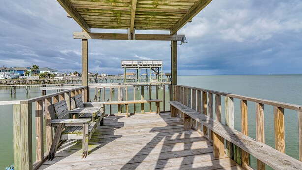 A wooden deck with benches and a covered area overlooking a body of water. - Saltwater Pool! Epic Galveston Bay Group Getaway! (Dickinson)