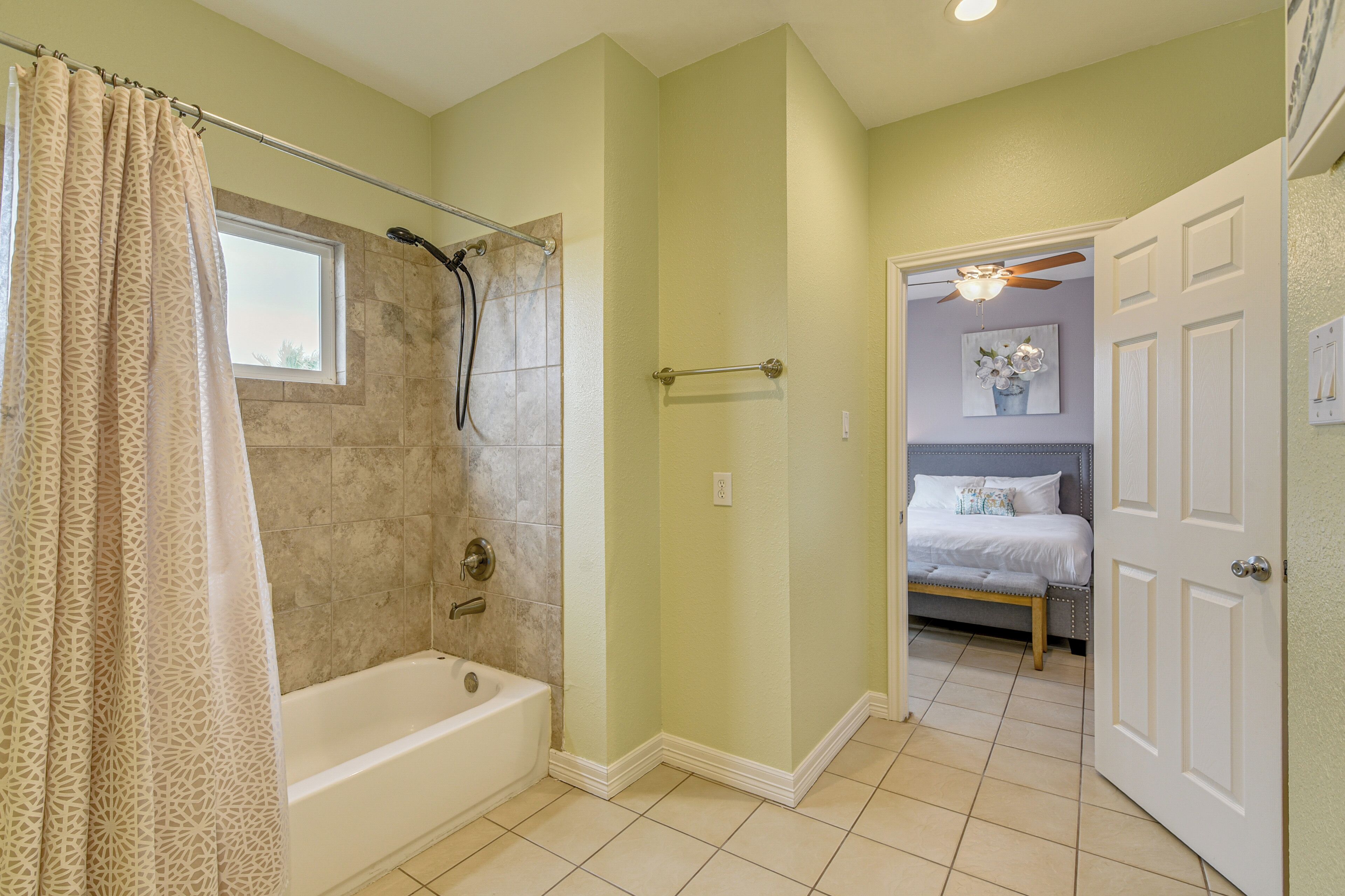 A bathroom with a bathtub, shower, and a window.