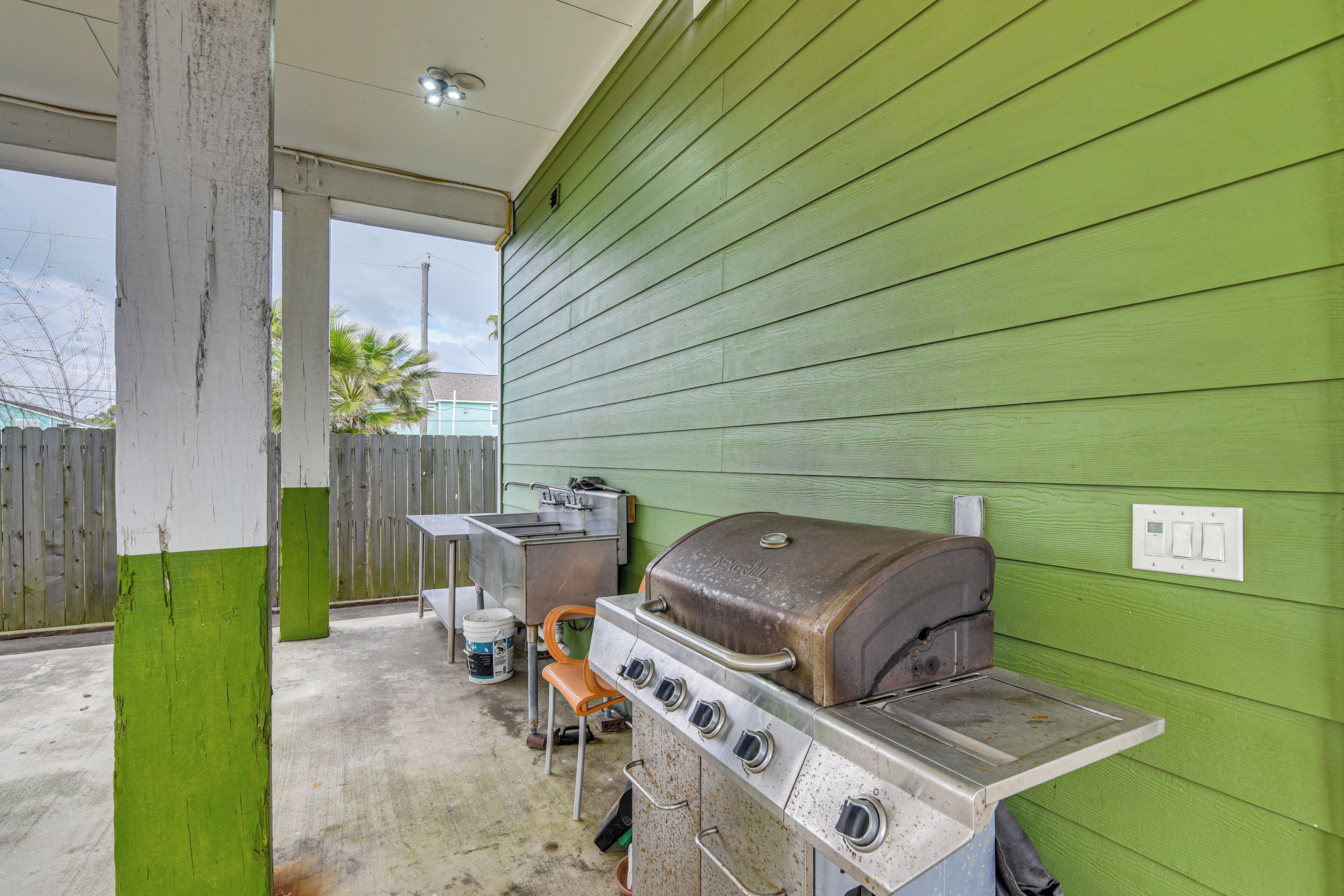 A covered outdoor area with a grill and a sink.