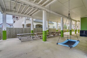 Un'area esterna coperta con tavoli da picnic e un'altalena.
