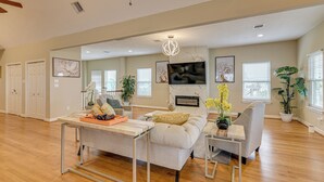 A spacious living room with a sofa, coffee table, and TV. There are potted plants and artwork on the walls. - Saltwater Pool! Epic Galveston Bay Group Getaway! (Dickinson)