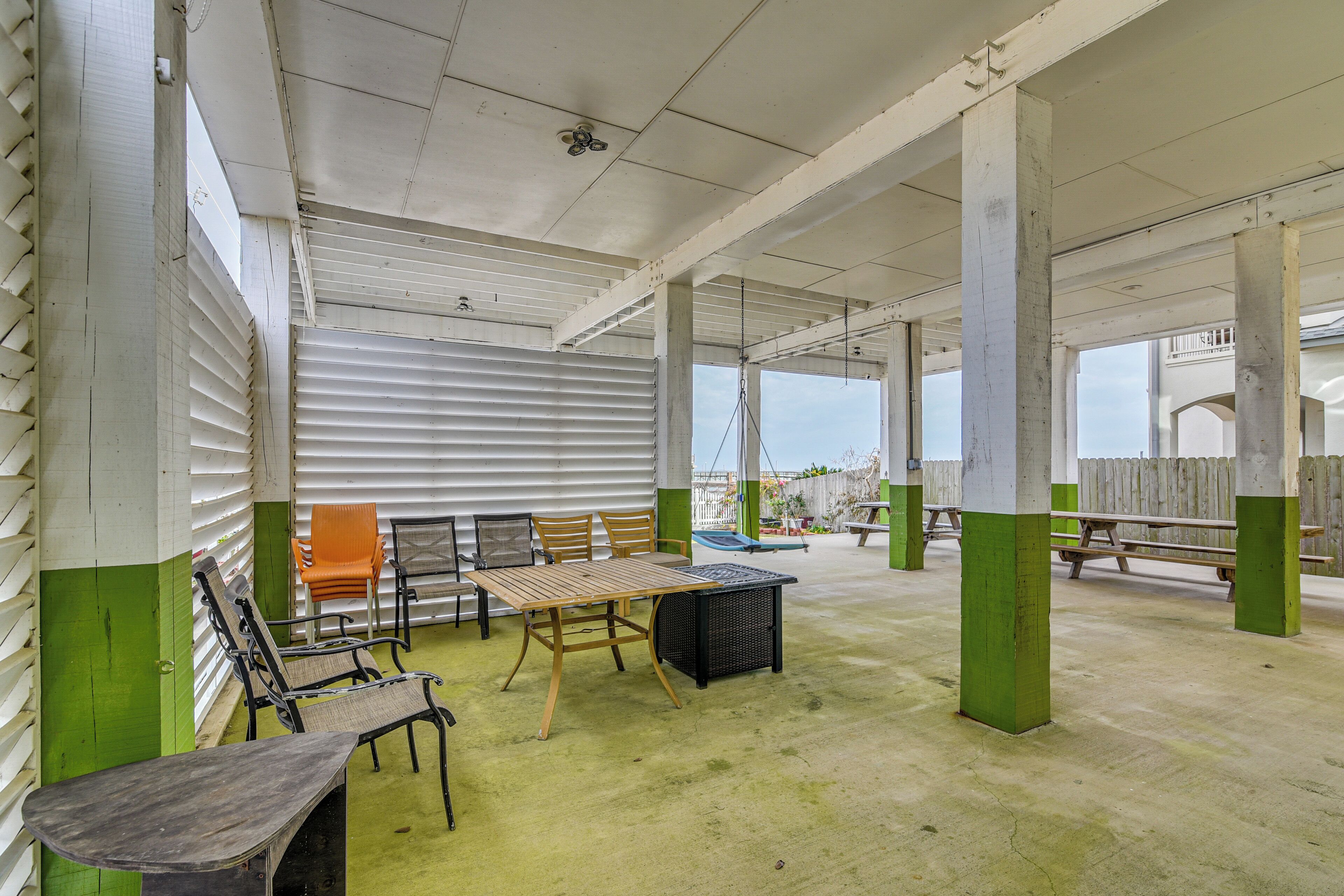 Een overdekte patio met een tafel en stoelen, een houten bank en een gezellige zithoek met uitzicht.