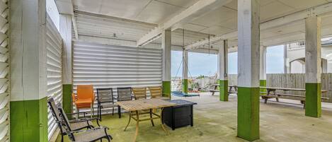 Een overdekte patio met een tafel en stoelen, een houten bank en een gezellige zithoek met uitzicht.