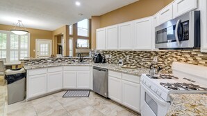 A kitchen with white cabinets, a stainless steel dishwasher, a gas stove, and a microwave. - 3,500-sq-ft Retreat w/ Private Yard in Sugar Land! (Sugar Land)