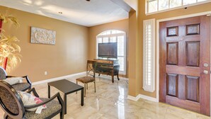 A living room with a TV, a wooden door, and a window. - 3,500-sq-ft Retreat w/ Private Yard in Sugar Land! (Sugar Land)