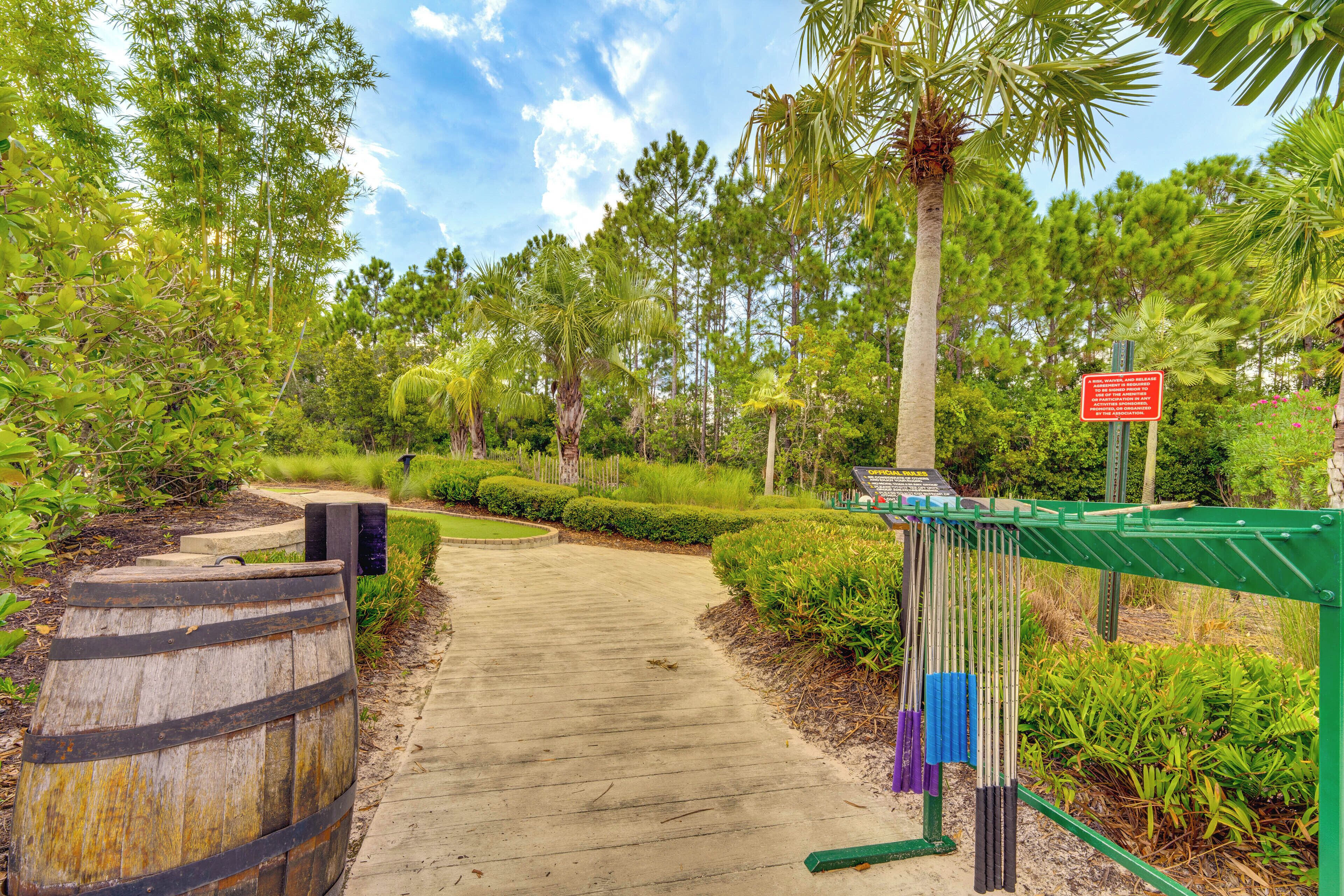 A pathway leading through a lush garden with various plants and trees.