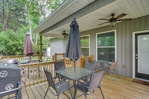 Une terrasse extérieure couverte, équipée d’une table et de chaises, d’un barbecue et d’un ventilateur de plafond.