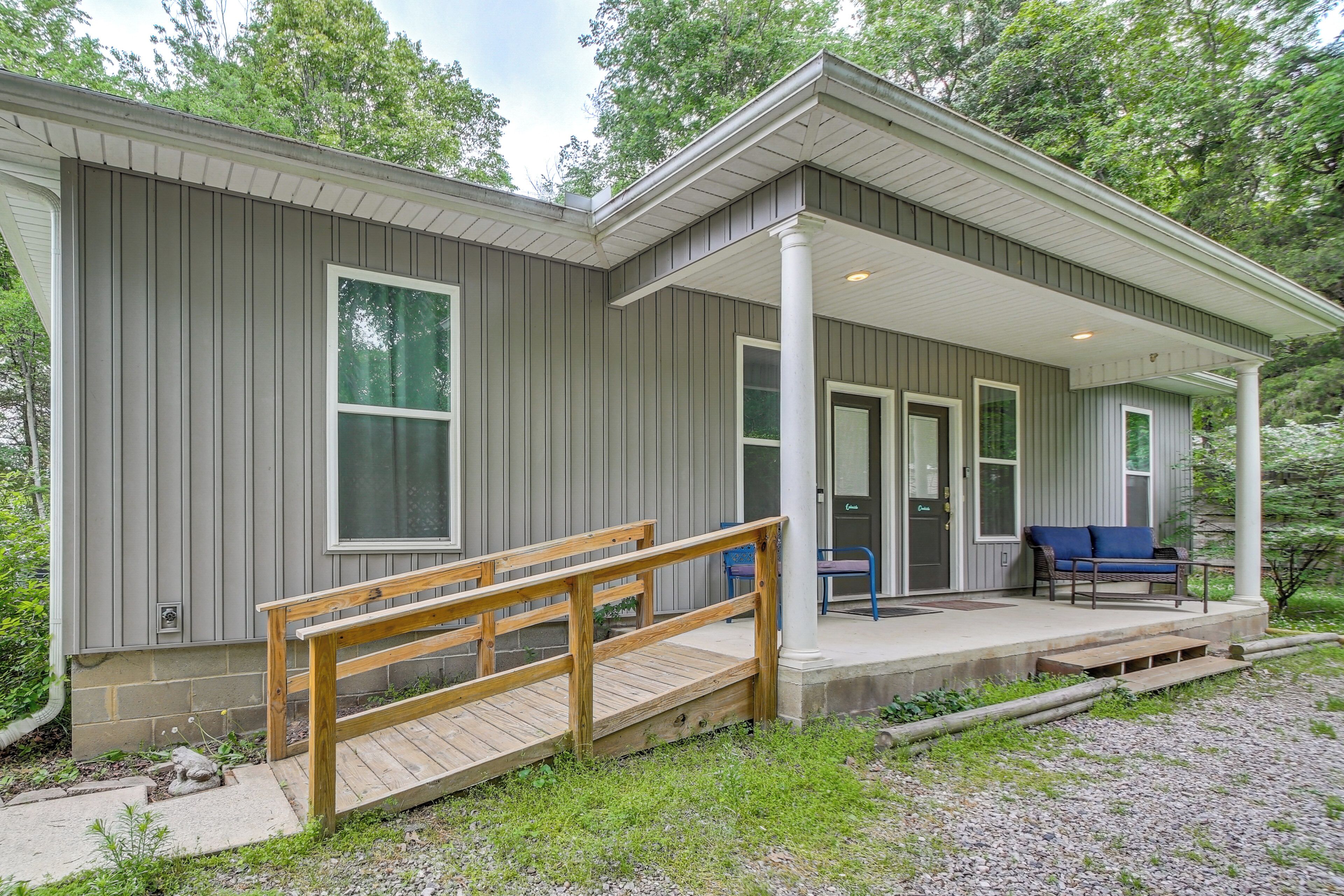 A modern house with a covered porch, a wooden staircase, and a bench.