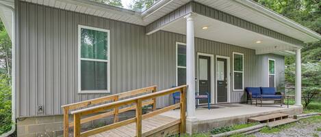 A modern house with a covered porch, a wooden staircase, and a bench.
