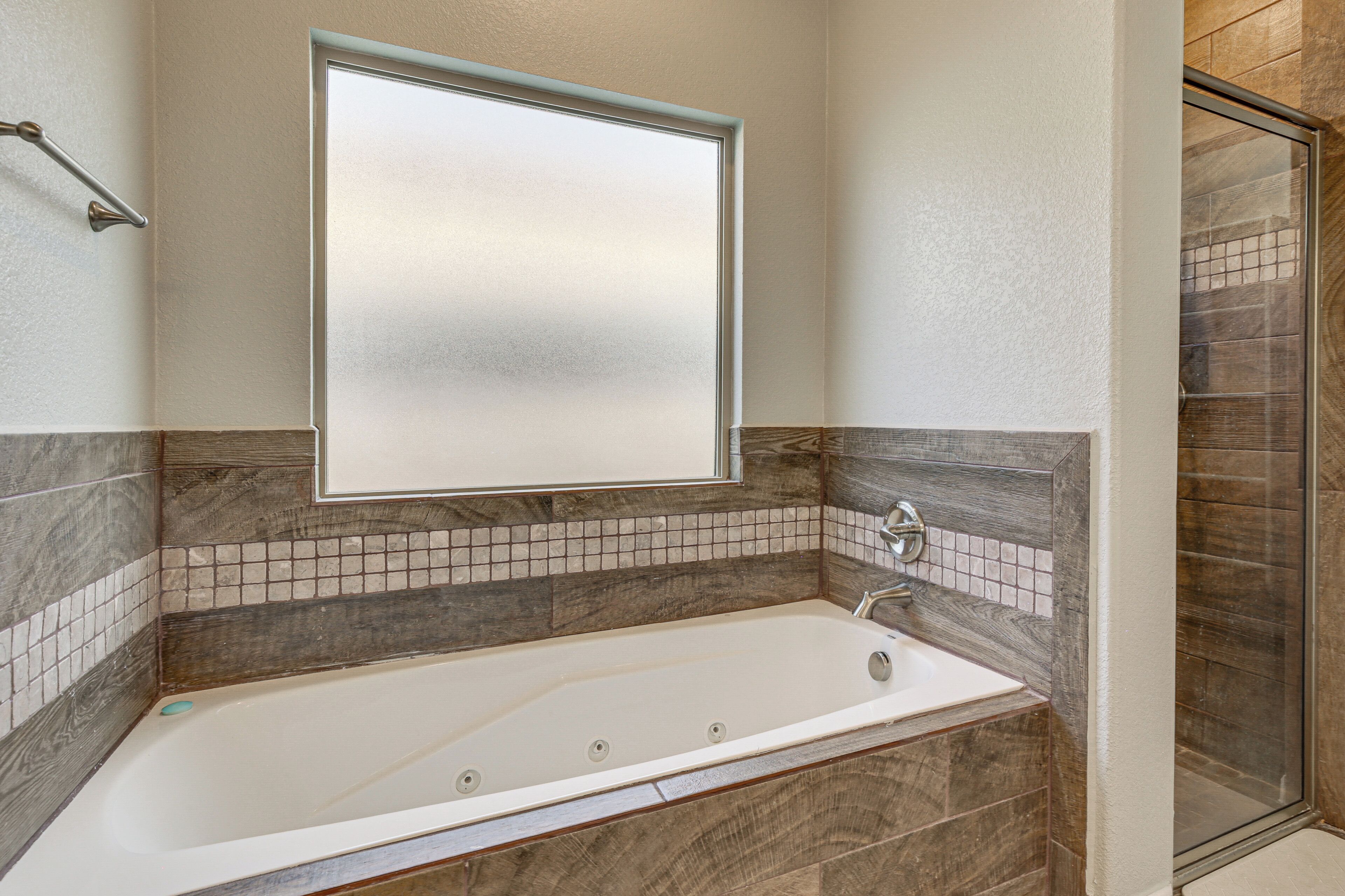 Une salle de bain moderne avec une baignoire sur pieds, une douche à l’italienne avec des parois en verre et un mur recouvert de carreaux.