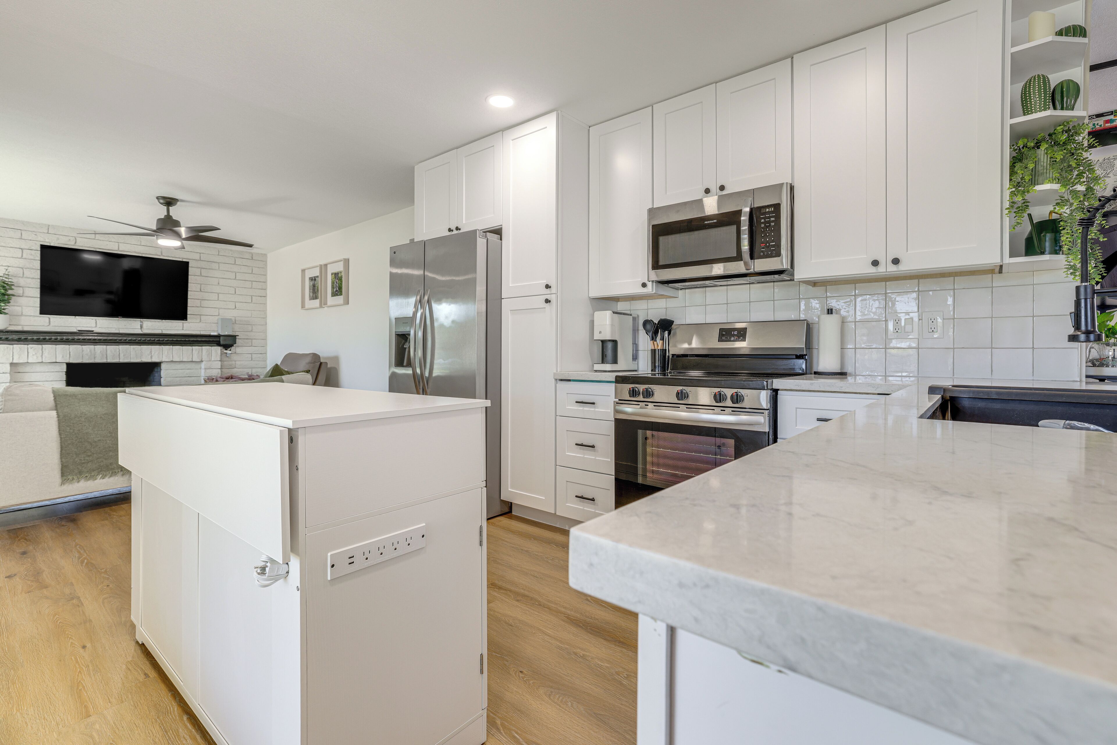 Una cocina moderna con armarios blancos, electrodomésticos de acero inoxidable y encimera de mármol.