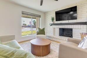 Una sala de estar con chimenea, televisor de pantalla plana y un ventanal grande.