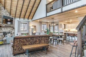 A spacious living area with a wooden bench, a stone fireplace, and a dining area with bar stools. - Trails, Golf & Beaches! Luxe Innsbrook Resort Stay (Wright City)