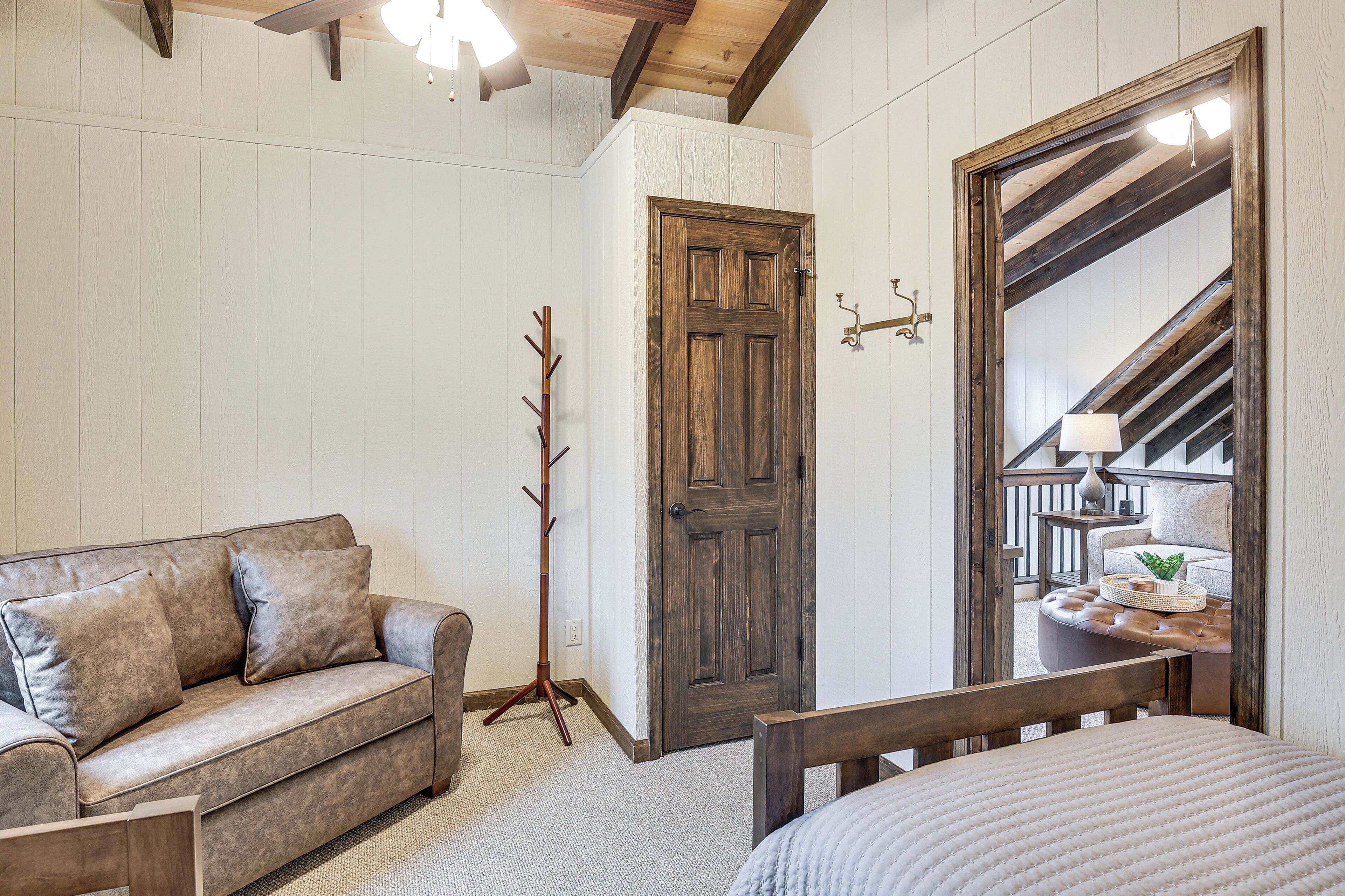 Una habitación con puerta de madera, espejo con marco de madera, un sofá y una cama.