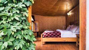 A wooden cabin bedroom with a bed, a nightstand, and a wooden ceiling. - Semba Retreat (Hunder)