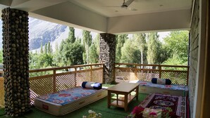 A balcony with a wooden railing, a sofa, a table, and a view of mountains. - Semba Retreat (Hunder)