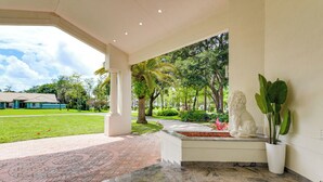 A covered outdoor area with a stone floor, a white statue, and a potted plant. - 8,100-sq-ft Parkland Estate w/ Luxe Outdoor Oasis! (Parkland)