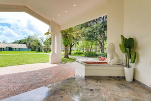 A covered outdoor area with a stone floor, a white statue, and a potted plant. - 8,100-sq-ft Parkland Estate w/ Luxe Outdoor Oasis! (Parkland)